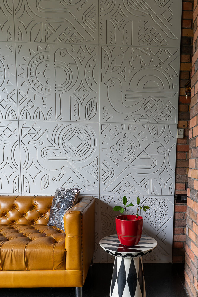 Carved relief wall panels behind a tan leather Chesterfield sofa